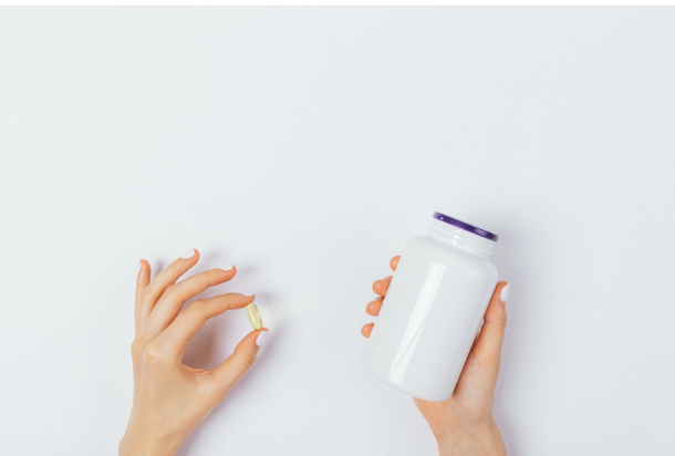 Woman holding magnesium supplement capsule and bottle symbolizing daily supplementation for stress and mood support.